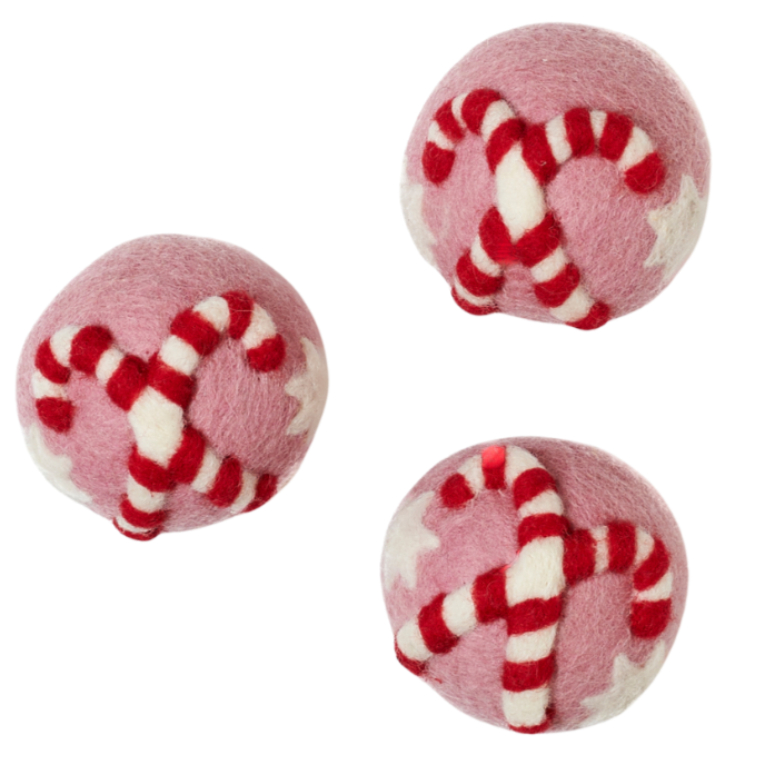 Three pink and white candy cane patterned dryer balls on a white background