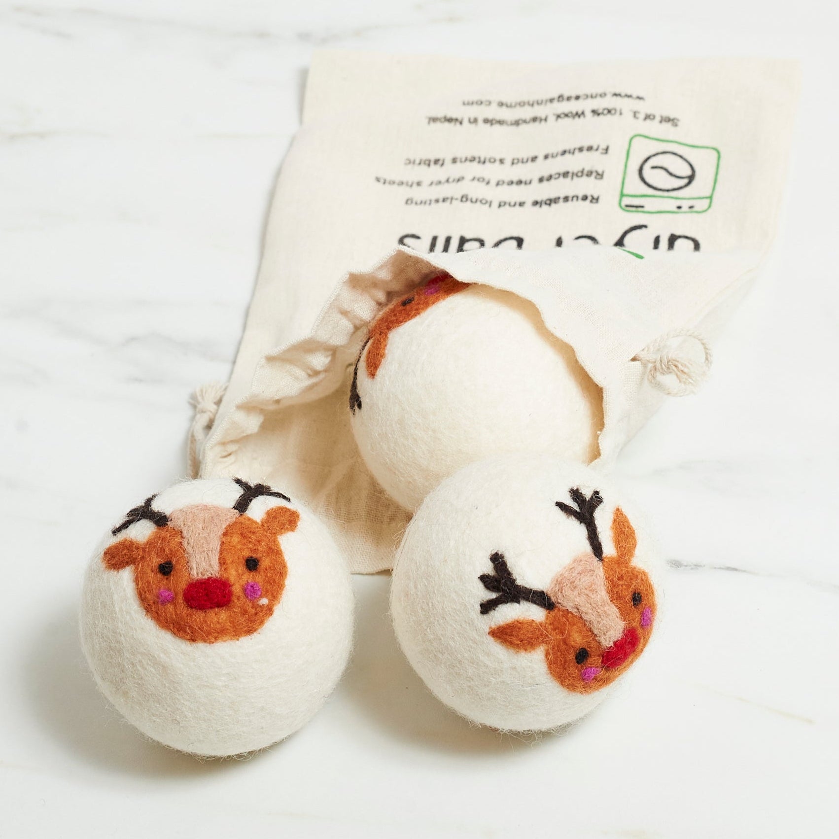 Three dryer balls with reindeer faces on a white background