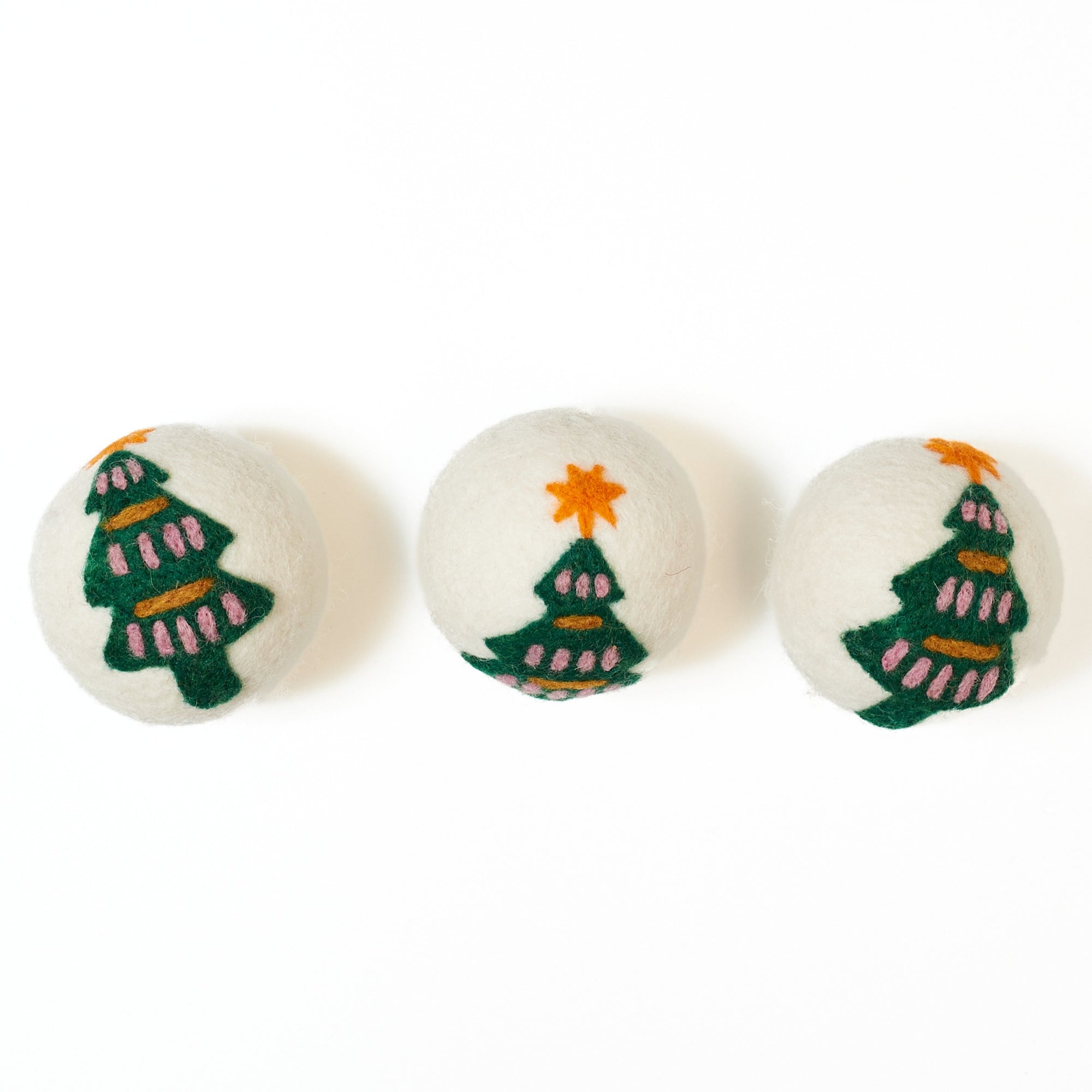 Three dryer balls with Christmas tree designs on a white background