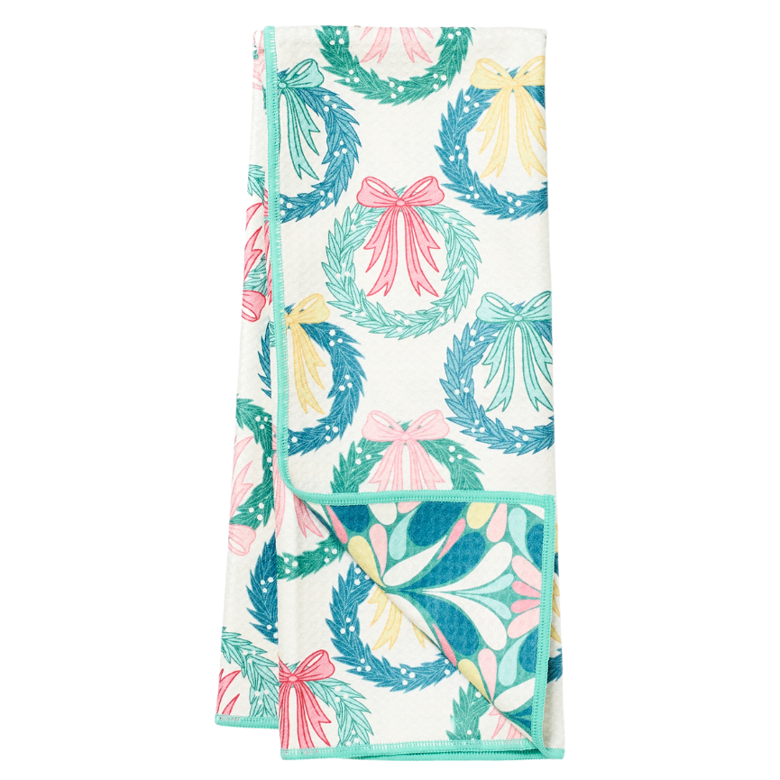 Folded tea towel from Rebecca Jane Woolbright with wreath and bow pattern on a white background